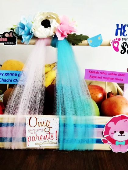 A healthy and beautiful option for a baby shower. This fruit basket is decorated with a 'He or She' theme, combining fresh fruits with cute baby-themed decorations.