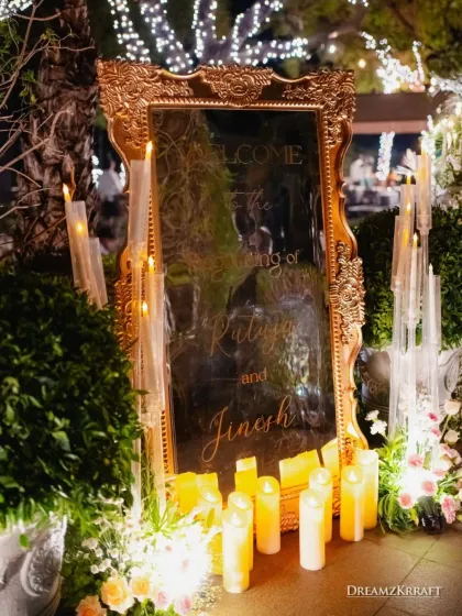 A personalized welcome sign etched onto an ornate, gold-framed mirror, surrounded by candles and flowers. This is how I greet guests with elegance and a personal touch.