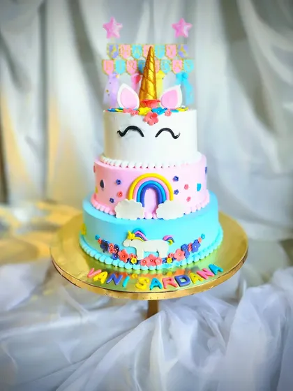 A vibrant three-tier unicorn cake in our bestselling Funfetti flavor. This cake is a rainbow of colors, decorated with a golden horn, flowers, and a cute unicorn figure.
