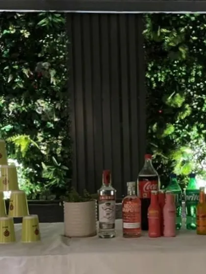 Let the games begin. A bar setup with drinks and cups stacked for party games, set against our signature green walls.