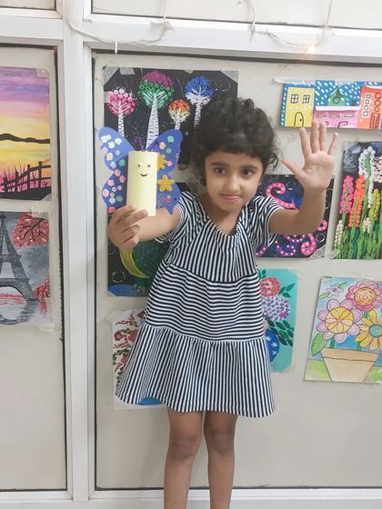 Another happy student waving with her butterfly craft. These simple projects build confidence and teach important lessons about recycling.