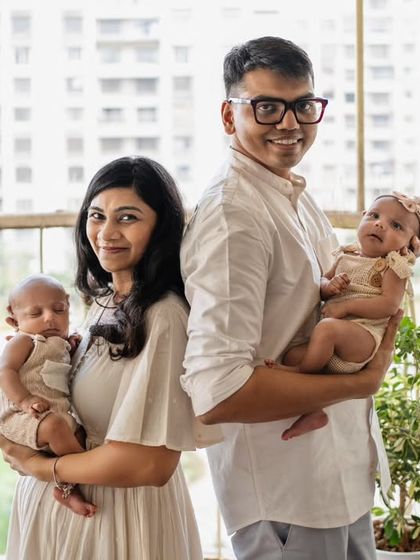 A modern family portrait with newborn twins. This photo, taken on a balcony with natural light, feels fresh, authentic, and full of love.