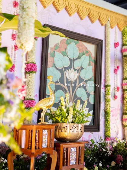 It's all in the details. This close-up from a traditional naming ceremony highlights the blend of textures and elements, from the hand-painted lotus art and brass peacock to the fresh floral garlands, all coming together to create a rich, cultural setting.