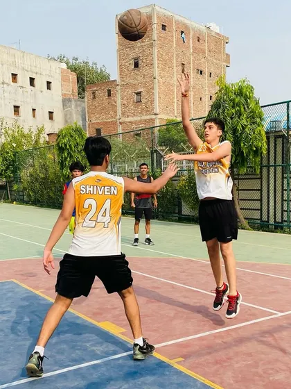 A player takes a mid-range jump shot while being closely guarded. This demonstrates the confidence we build in our players to take and make important shots.