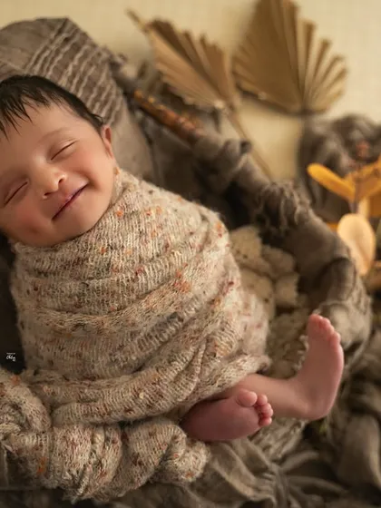 The sweetest smile from this little one, who is clearly having happy dreams. The warm, brown tones of the wrap and props are perfect for a cozy, autumn feel.
