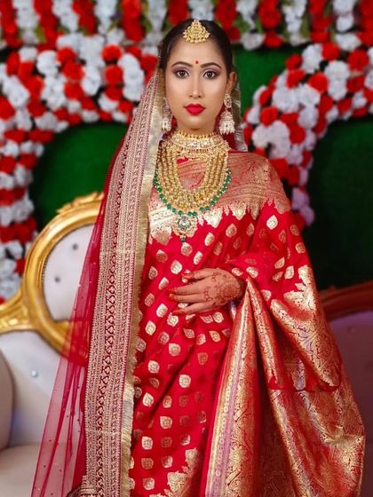 A full-length view of the bride in her beautiful red Banarasi saree. The makeup is designed to complement the richness of the fabric and the grandeur of the occasion.