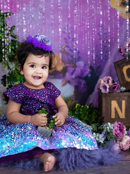 A bright smile from this little girl in her shimmering purple and blue dress.