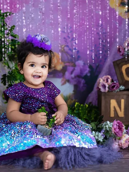 A happy smile in a magical purple wonderland. The sparkling lights and floral details create a beautiful and festive birthday scene.