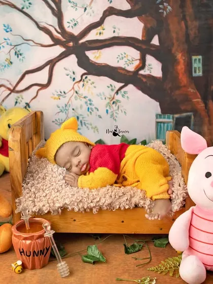 A dreamy Winnie the Pooh themed newborn shoot. This little one, dressed as Pooh, is sleeping soundly in a tiny bed surrounded by his friends from the Hundred Acre Wood.