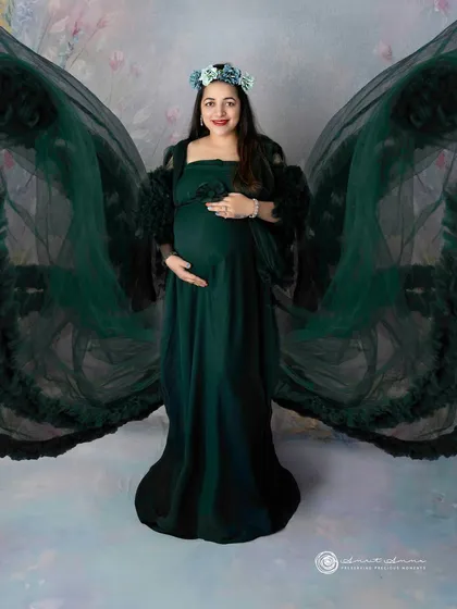 A breathtaking portrait in a deep emerald green gown with dramatic wing like sleeves. This look is for the mother who wants to feel like a goddess.