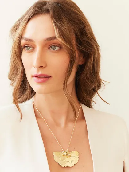 A classic portrait where the lighting and simple white blazer frame the statement necklace perfectly.