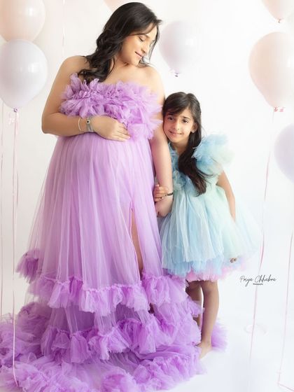 A quiet moment between mother and daughter. The matching color tones of their dresses and the gentle hand-holding create a beautiful and connected family portrait.
