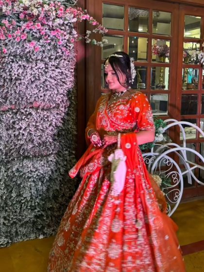 A candid shot of a client in a vibrant orange lehenga at a wedding function.