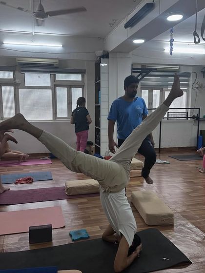 This practitioner holds a wide-legged variation in his headstand, showcasing advanced control and flexibility.