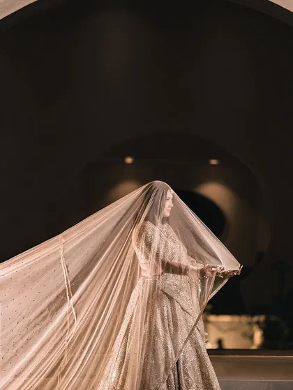 A duplicate of the stunning artistic shot of the bride with her long, flowing veil against a circular architectural feature.