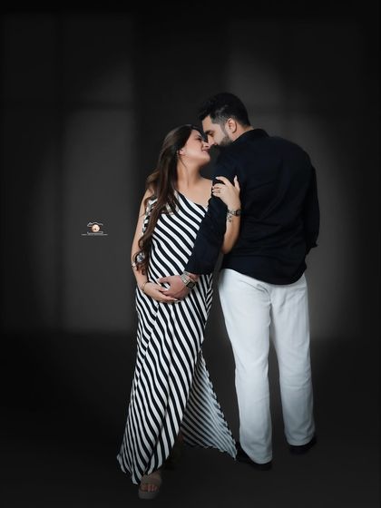 An intimate pose where the couple, dressed in black and white, look into each other's eyes. The simple background keeps the focus entirely on their connection.