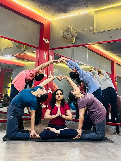 A creative group pose forming a heart shape, with one student meditating peacefully in the center. This is a fantastic team-building exercise.