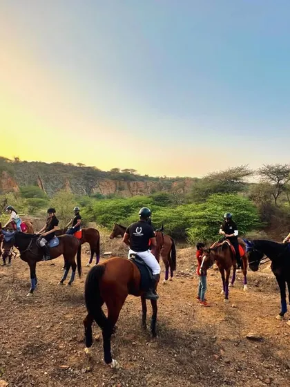 A wide shot of one of our safari groups with their guides, set against the vast, natural landscape of the Aravalis at dusk.