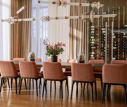 A dramatic view of a Luna chandelier in a formal dining room with a built-in wine rack. The lighting enhances the sophisticated atmosphere, making it ideal for entertaining.