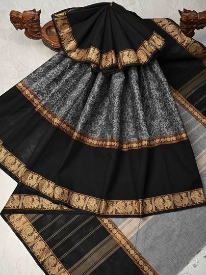 A classic black and grey cotton saree with a traditional peacock border. This is a versatile and elegant piece that is perfect for both work and casual wear.