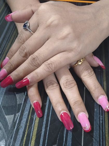 A dramatic manicure combining hot pink and deep red gel polish on long, square extensions. The silver glitter line adds a touch of separation and sparkle.
