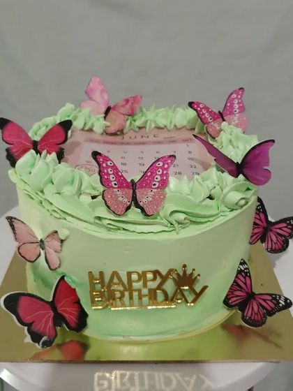 A lovely green cake with a calendar marking a June birthday, decorated with pink butterflies.