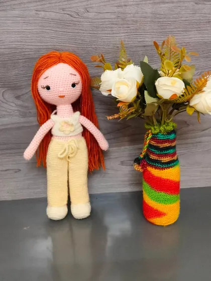 Here is the same doll with long red hair, standing next to a vase. She is very elegant.