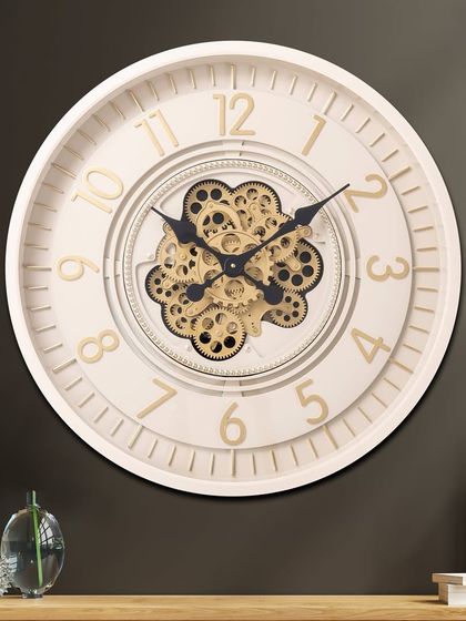 The Lunar Echo luxury designer wall clock features a clean white frame with gold numerals. The central moving gear mechanism adds a touch of industrial chic to its otherwise minimalist and modern design.