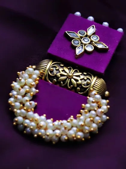A close-up focusing on a single purple earring to showcase the detailed metalwork and pearl clusters.