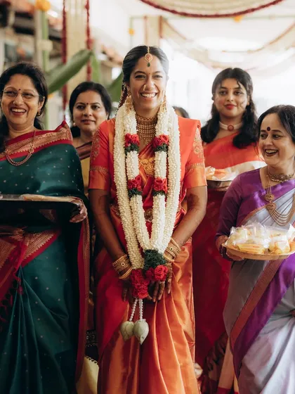 A radiant bride during her temple wedding entrance, surrounded by the women in her family. Her joyful smile says it all.