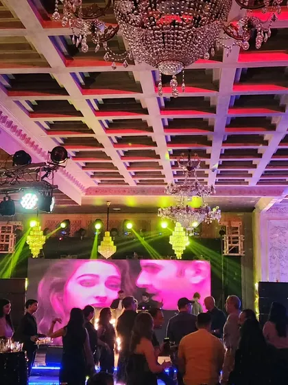 Guests enjoying the music at a sangeet night, with a large LED screen displaying visuals that match the energy of the songs. This adds a dynamic visual element to the party.