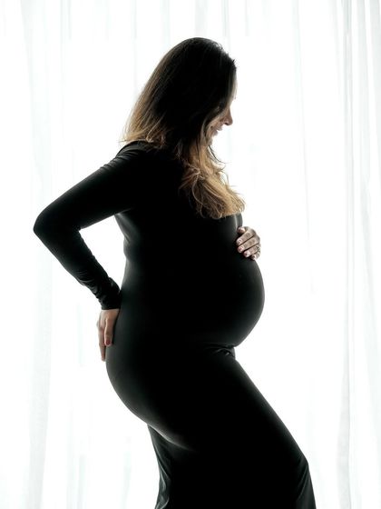 A classic silhouette portrait against a bright window, highlighting the beautiful curve of the baby bump.