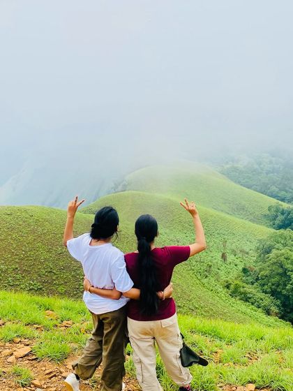Friends for life, made on the trail. Two trekkers celebrating their climb with a view of the beautiful Netravati landscape.
