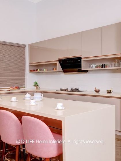 A sleek, modern kitchen with handleless beige cabinets and an island with pink bar stools. The design is minimalist, clean, and incredibly stylish.