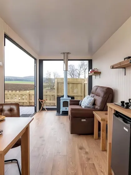The interior of this container home features a cozy living and dining area with a wood-burning stove. It’s a perfect example of how we create warm and inviting spaces for any climate.