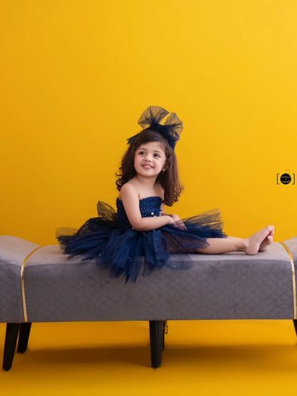 Blue-tiful inside and out. This little girl relaxes on a bench, looking chic and happy in her navy tulle dress.