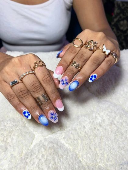 A beautiful blue and white set with a mix of French tips, ombre, and delicate floral patterns.
