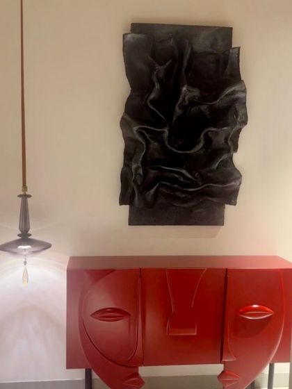 This dramatic black sculptural artwork installed in a client's home in Kanpur. It's placed above a bold red console, creating a stunning and high-contrast focal point in the entryway.