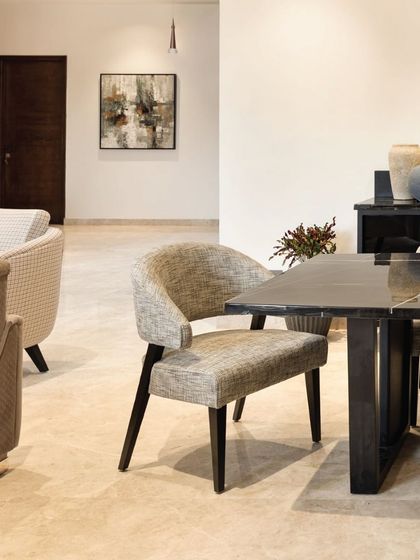 An open-plan design connects the dining and living areas on the first floor. The material palette of textured upholstery, dark wood, and polished marble creates a cohesive flow, making the space feel both unified and expansive.