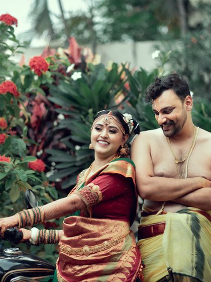 A fun and unique portrait of a traditionally dressed South Indian couple posing with a motorcycle, blending tradition with a modern, playful twist.