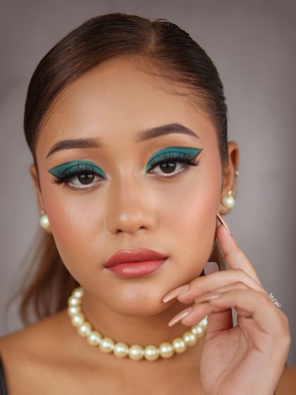 A fusion makeup look with a bold, graphic teal winged eyeshadow. Paired with a simple pearl necklace, this look is a perfect blend of modern art and classic elegance.