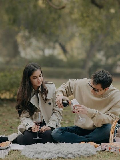 Pouring a glass of wine during a picnic shoot. We focus on the small, narrative details that make a pre-wedding session feel like a real, cherished memory.