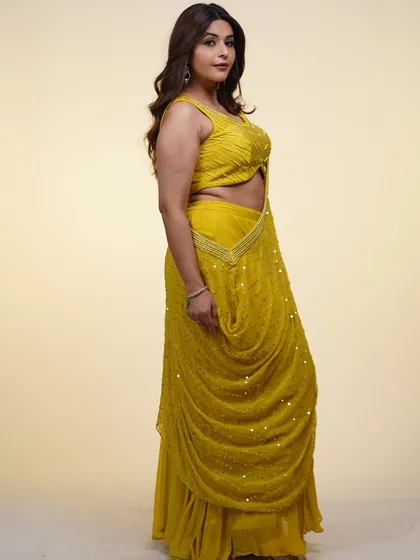 This yellow pre-draped saree is a burst of sunshine. The draped silhouette is flattering and easy to wear, while the embellished blouse adds a touch of glam.