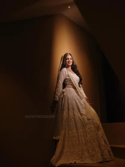 A stunning bridal portrait on a staircase, using dramatic lighting to highlight the bride and her elegant white lehenga.