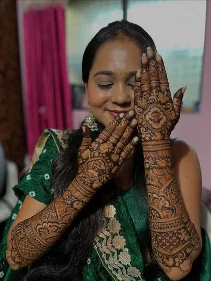 Another happy bride, her eyes closed in a moment of bliss. Her hands are adorned with a full, intricate bridal design featuring beautiful rose motifs.
