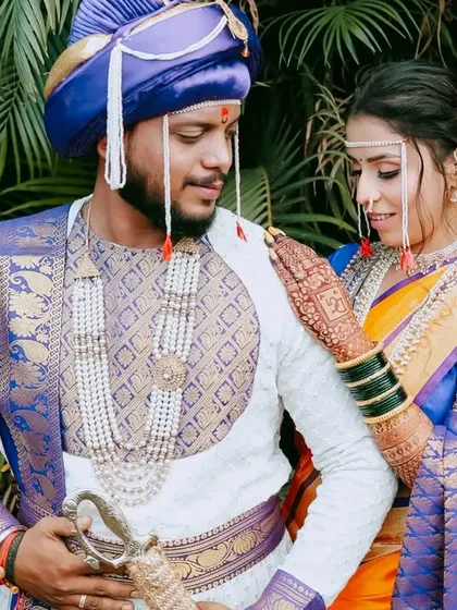 A classic portrait of a Maharashtrian couple against a lush green backdrop. The vibrant colors of their outfits and the natural setting create a beautiful contrast.