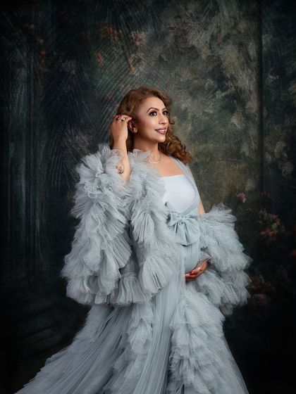 A beautiful close-up in a stunning grey ruffled gown. The painterly background and soft lighting create a sophisticated and elegant mood for this maternity portrait.