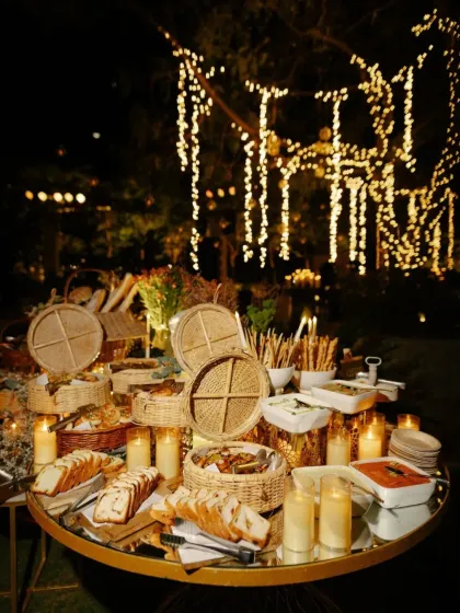 A beautiful bread and cheese grazing table at a candlelit welcome dinner. The presentation is rustic yet elegant, perfectly matching the warm and intimate ambiance.