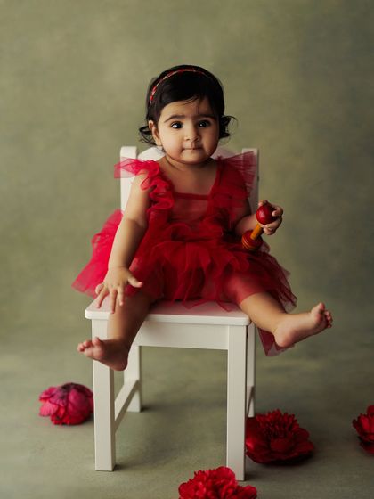 Cuteness overload. This little girl in her red dress is sitting on a small white chair, surrounded by peonies. A perfect setup for a classic, sweet portrait.