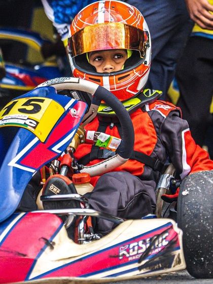 A young driver in his Kosmic kart, ready in the pit lane.